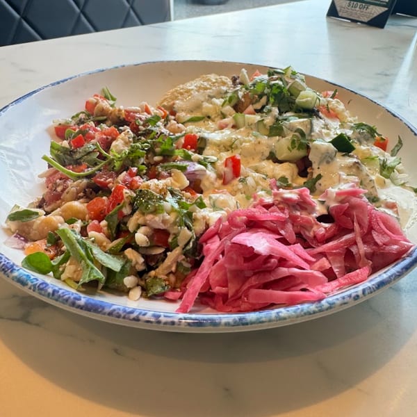 A colorful Mediterranean bowl from Tazā with hummus, salad, and pickled red cabbage.